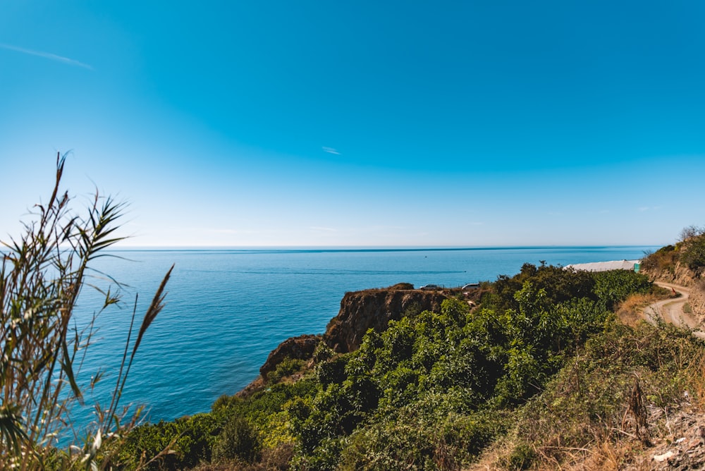 Montaña marrón y verde junto al mar azul bajo el cielo azul durante el día