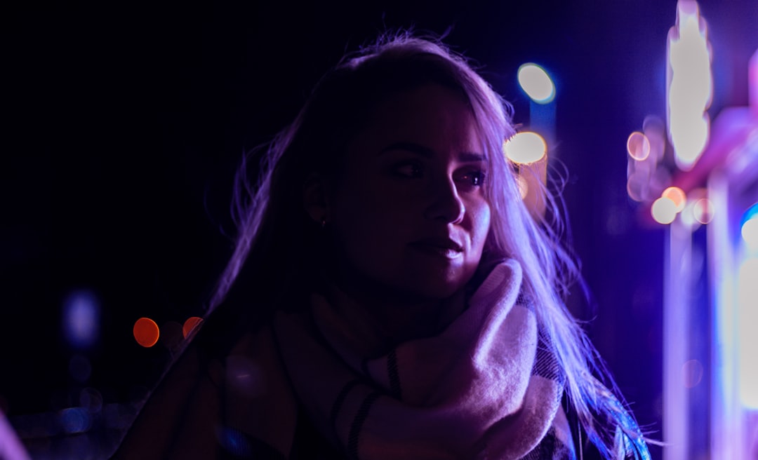 woman in black scarf with purple light in background