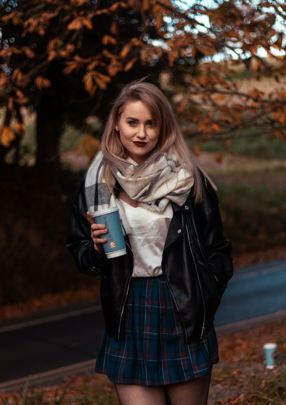 woman in black coat holding white ceramic mug