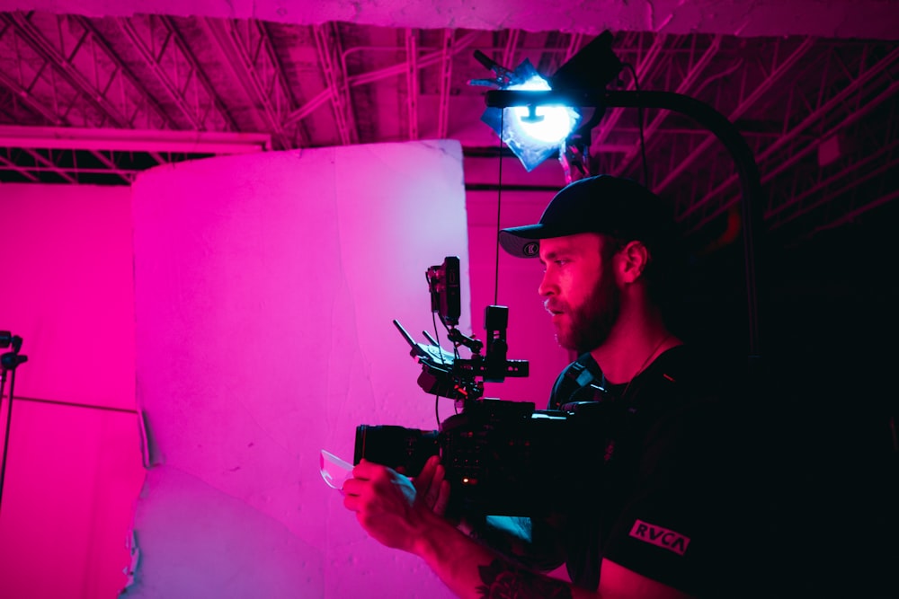 man in black polo shirt holding black video camera