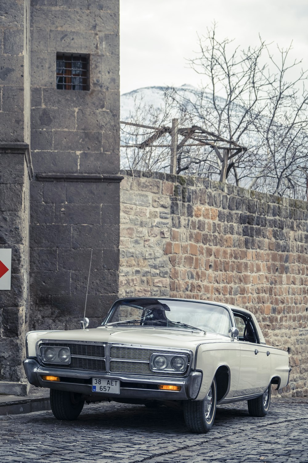 black car parked beside brown brick wall