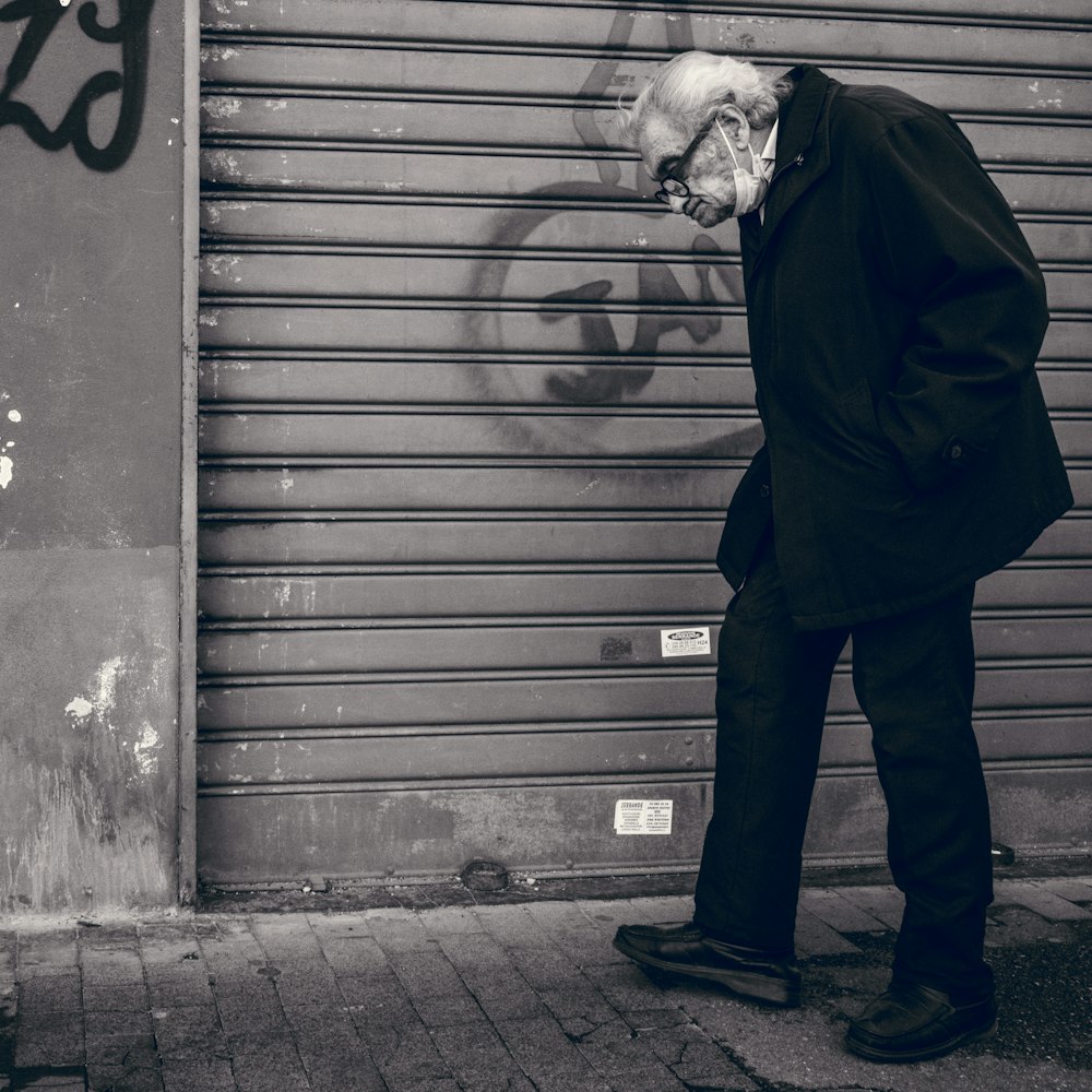 man in black coat standing beside wall