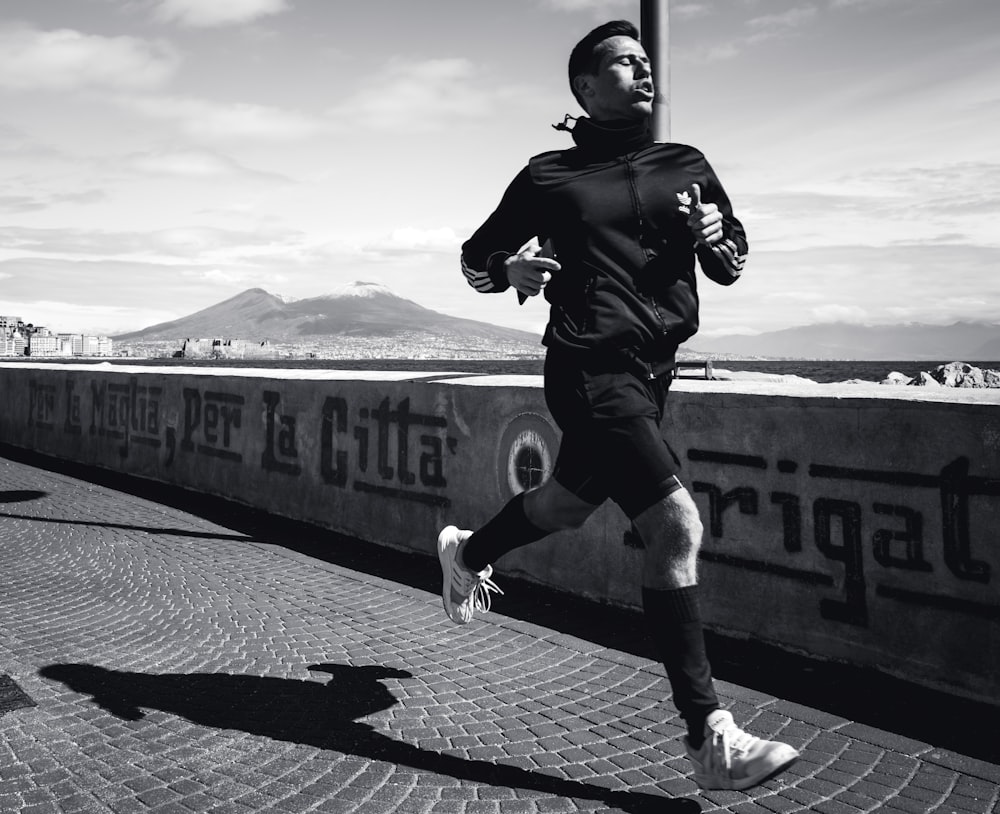 uomo in giacca di pelle nera che corre su strada