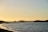 A serene Mediterranean coastline at sunset, with gentle waves lapping against rocky shores under a warm, golden sky.