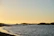 A serene Mediterranean coastline at sunset, with gentle waves lapping against rocky shores under a warm, golden sky.