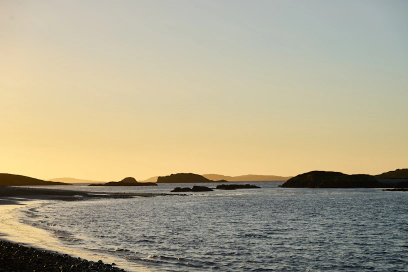 A serene coastal view at sunset with soft sandy beaches and calm blue waters.