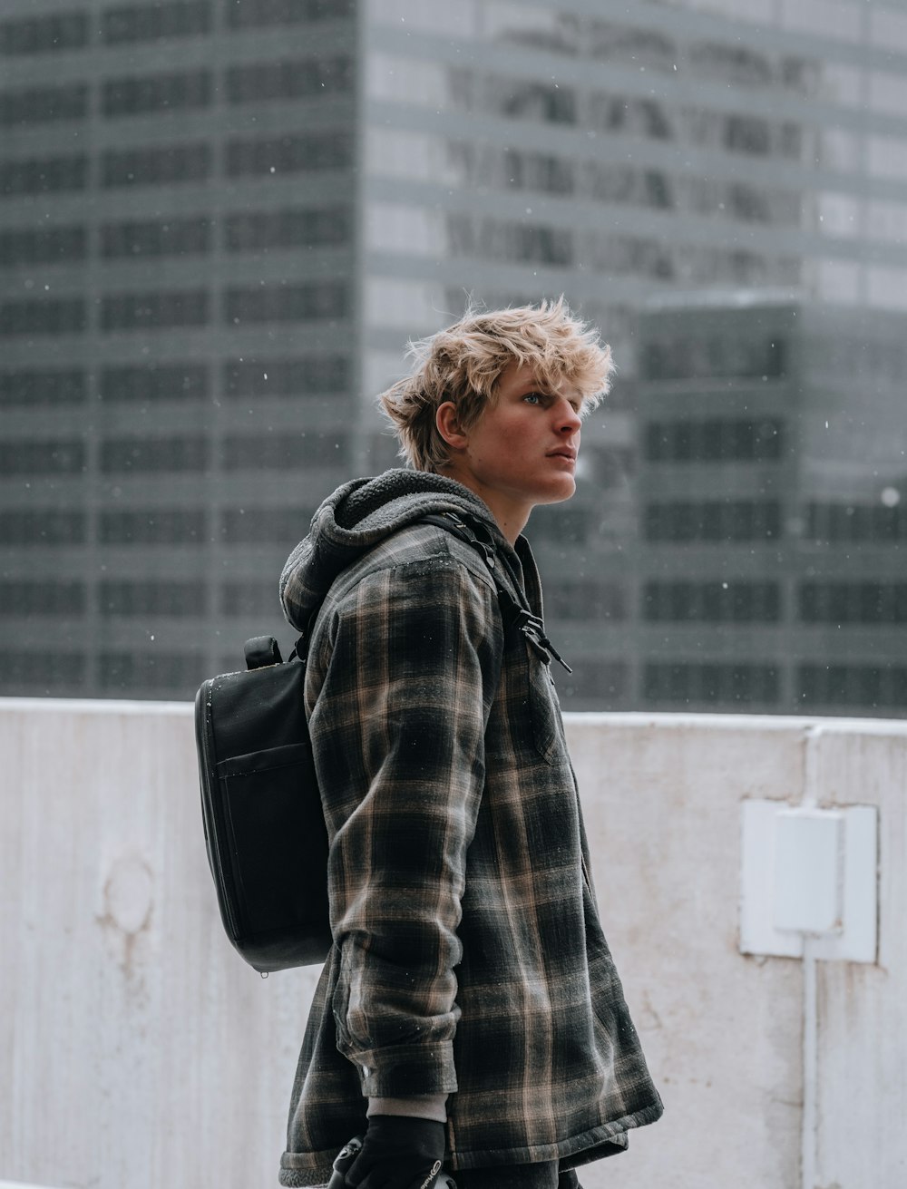 man in black and white plaid coat standing near white wall during daytime