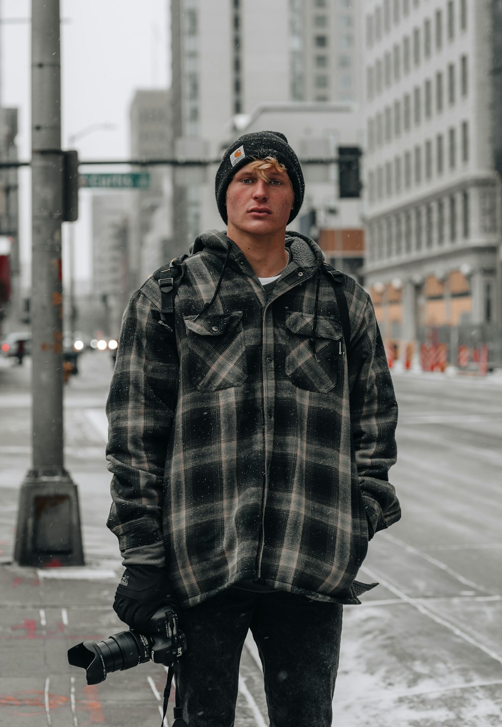 man in black and white plaid coat standing on sidewalk during daytime