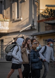 A group of happy teenagers with backpacks walking confidently in a safe school campus.