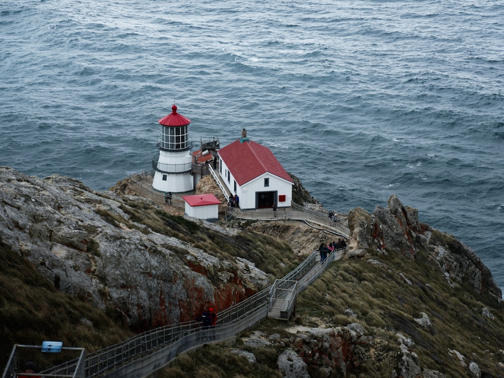 white and red concrete house on brown rocky mountain beside body of water during daytime