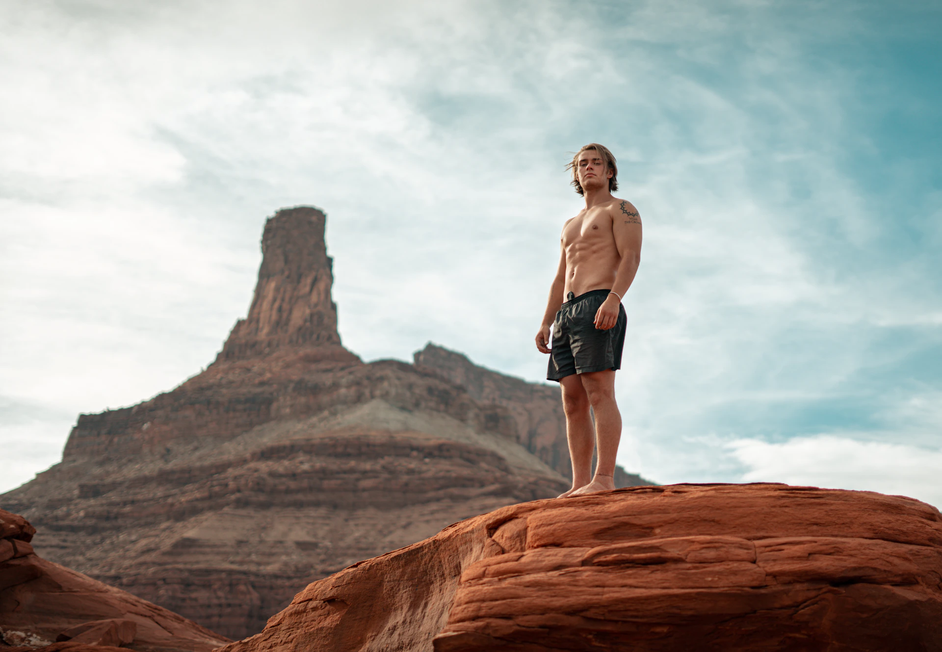 man in black shorts standing on brown rock formation during daytime