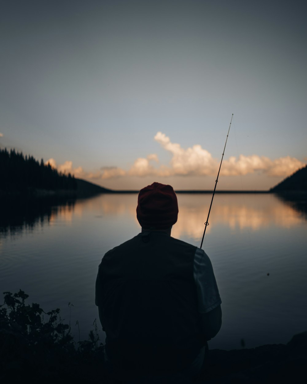 man in black jacket and black knit cap standing near lake during daytime