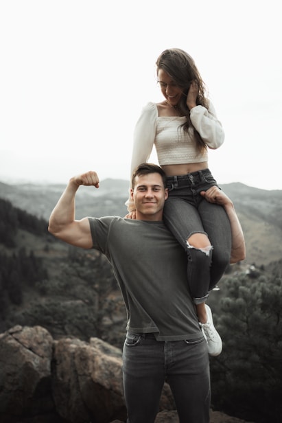 woman in white long sleeve shirt and blue denim jeans sitting on rock during daytime