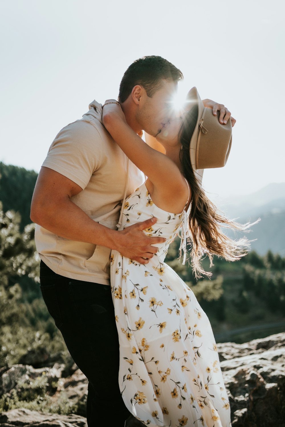 man in brown shirt kissing woman in white floral dress