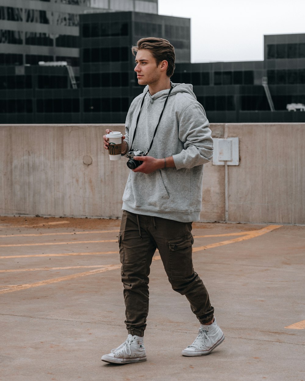 man in gray zip up jacket and blue denim jeans holding black ceramic mug