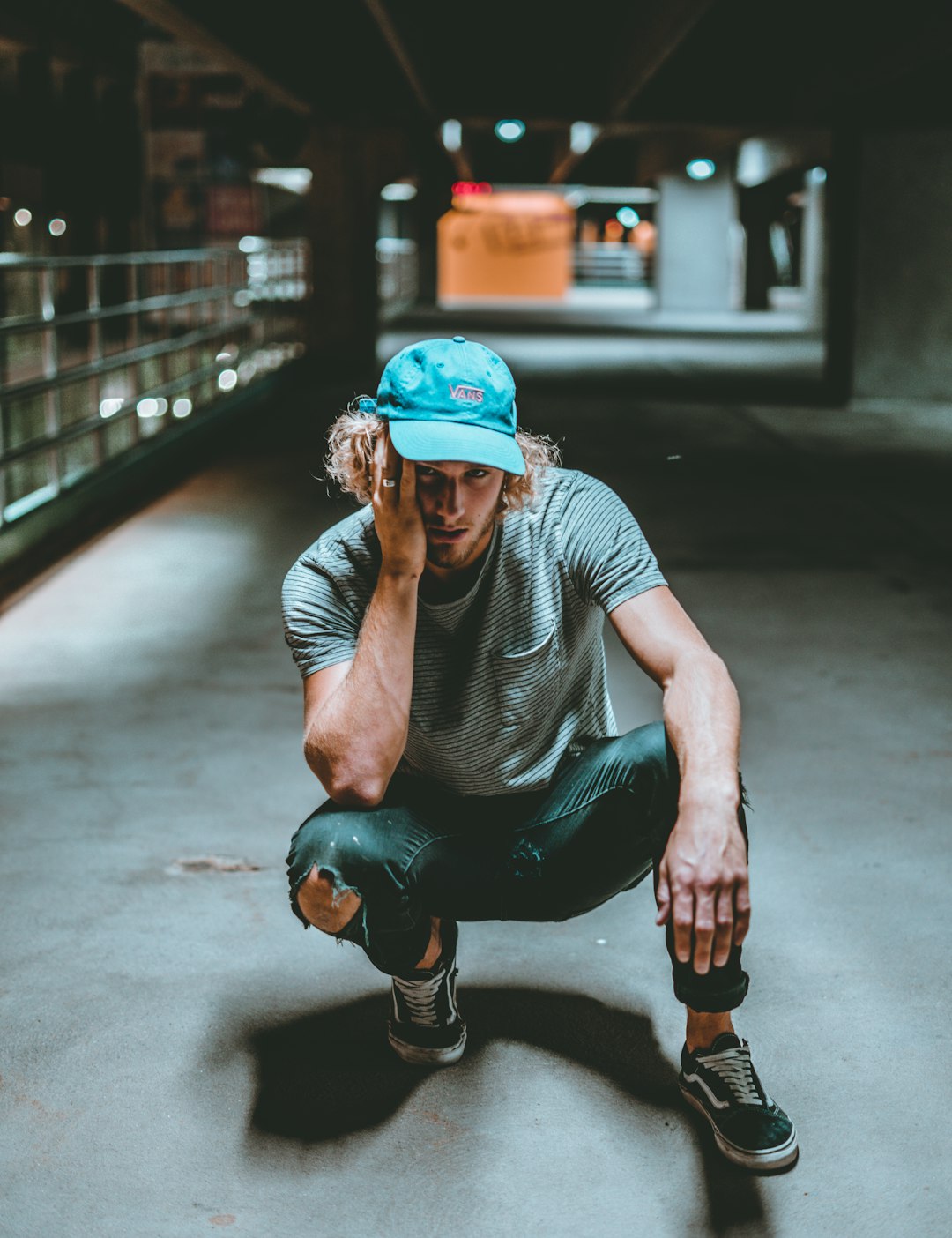 man in grey crew neck t-shirt and blue helmet sitting on grey concrete floor