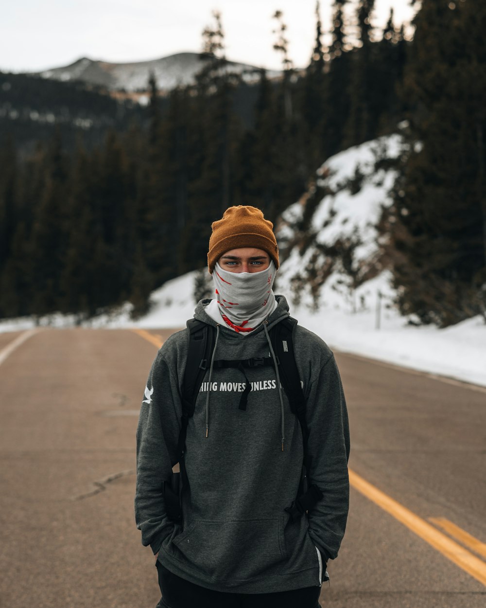 man in black jacket and brown knit cap standing on road during daytime