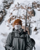A model wearing a sleek skahdi base layer under a ski jacket, standing against snowy mountain backdrop.