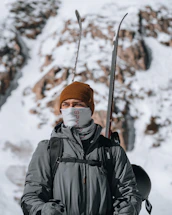 A cozy winter scene with a person wearing a thick jacket and gloves, standing beside a snow-covered mountain trail.