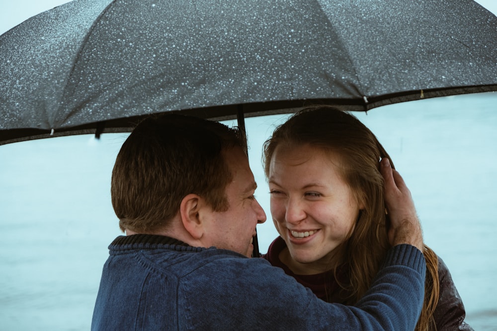 man and woman under black umbrella during daytime