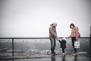 man and woman standing on gray metal fence during daytime
