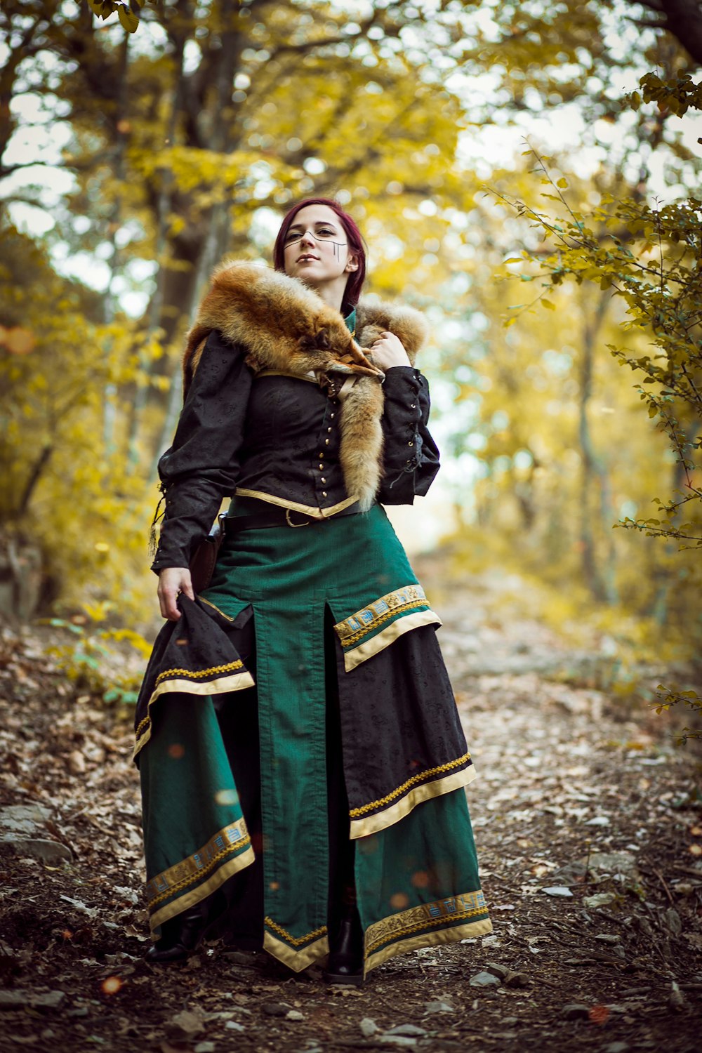 woman in black jacket and green skirt standing on forest during daytime