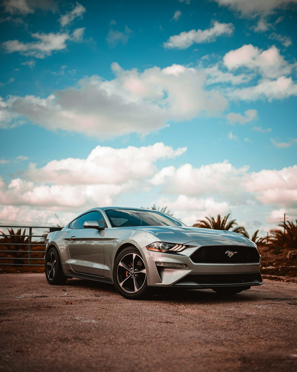 gray bmw coupe parked on gray asphalt road under blue and white sunny cloudy sky during