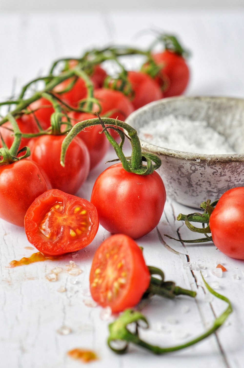 tomate rojo junto a un cuenco de cerámica blanca