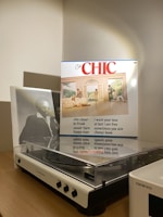 A vintage turntable sits on a wooden surface, next to a vinyl record cover featuring a group of people in a stylish, retro setting. The cover includes a list of song titles and the word 'CHIC' prominently displayed at the top. The lighting casts a warm glow, highlighting the turntable and the record.