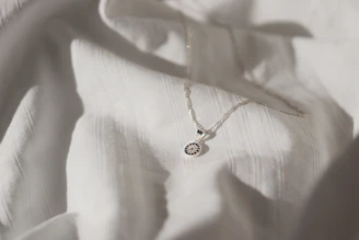 Close-up of a delicate sterling silver necklace resting on soft pastel green fabric, highlighting its fine craftsmanship.