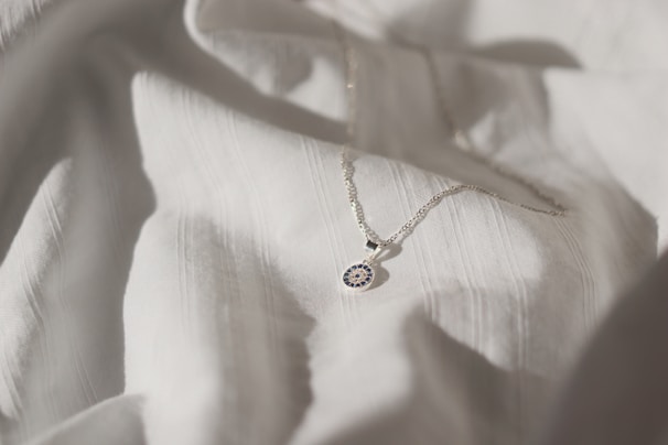 Elegant silver necklace with a delicate pendant displayed on a soft fabric background