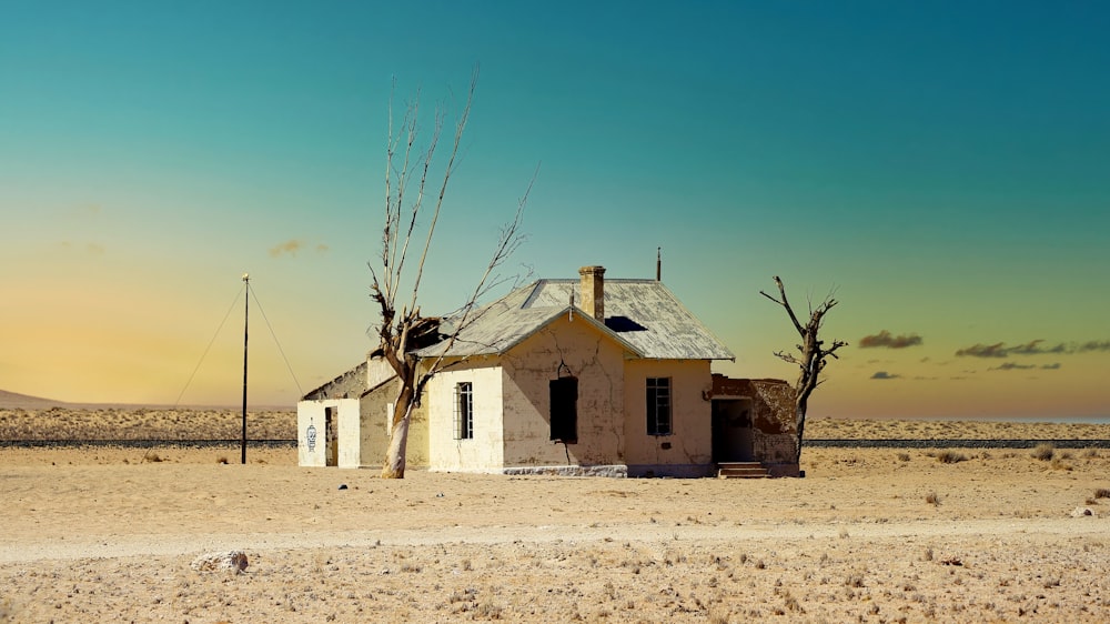 white concrete house near bare tree under blue sky during daytime