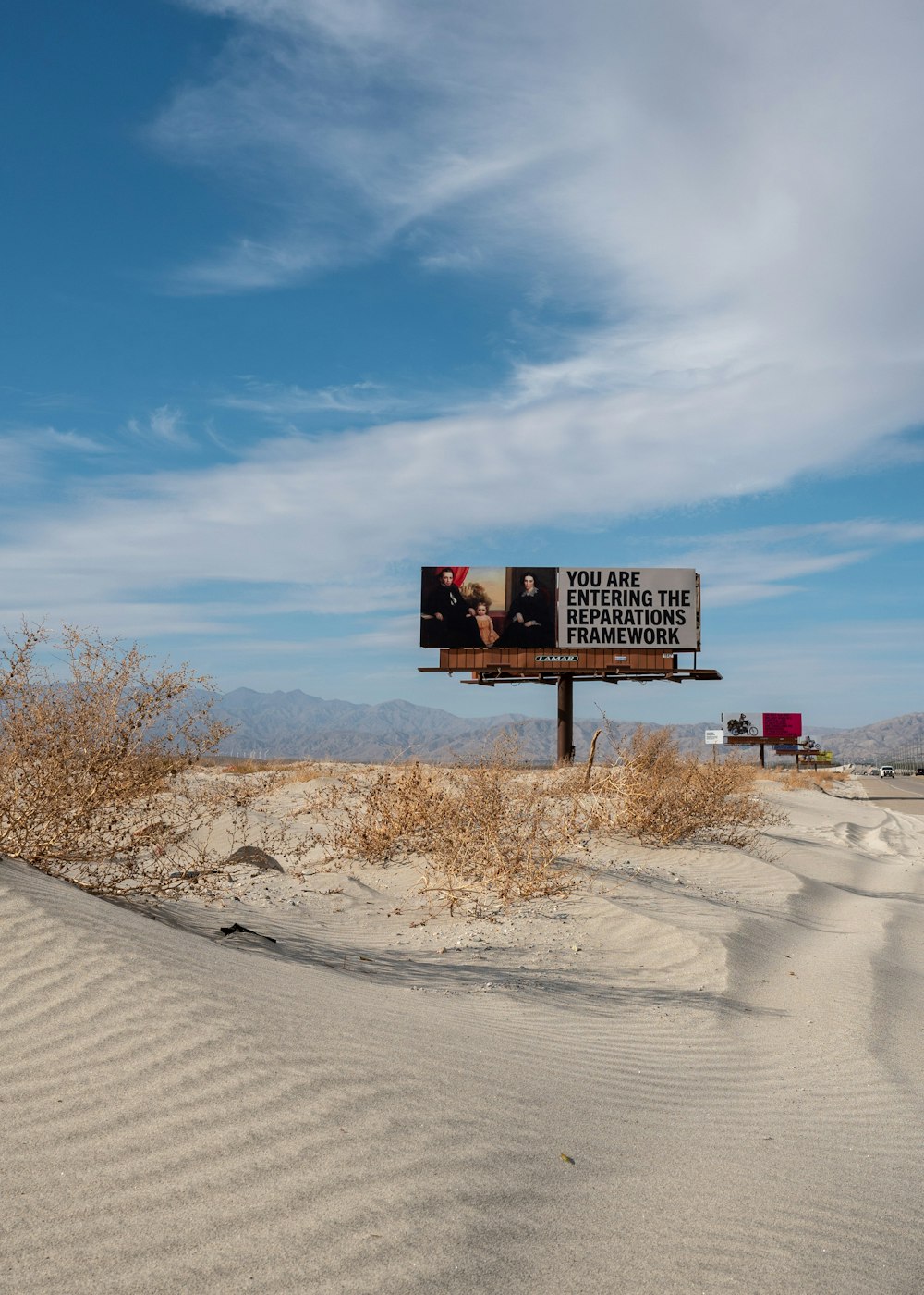 black and white street sign on brown sand under blue sky during daytime