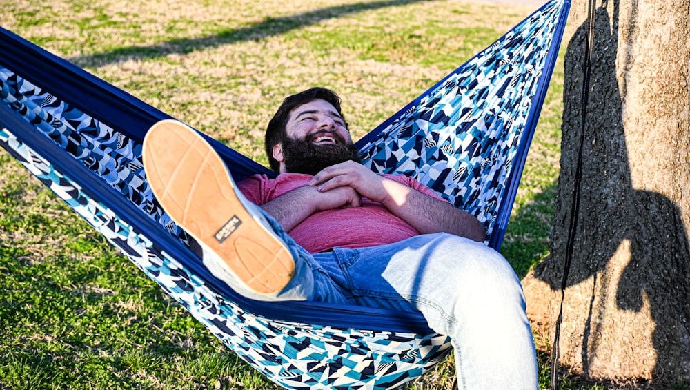 man in red shirt lying on blue and white hammock