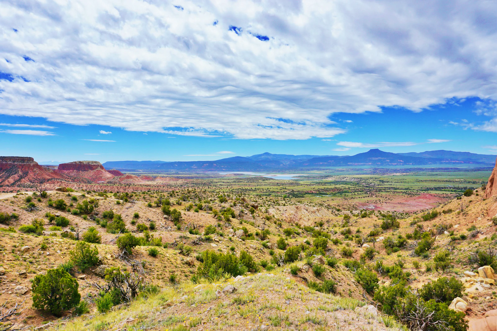 A wide New Mexico mesa and red rock landscape under a turquoise sky near Abiquiu