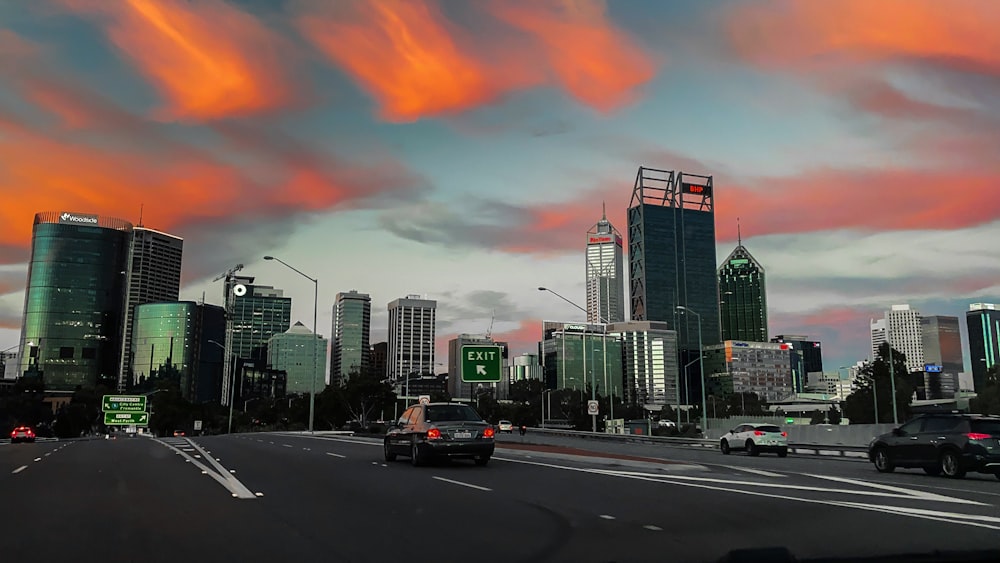 cars on road near city buildings during sunset