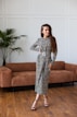 woman in black and white floral long sleeve dress standing beside brown couch