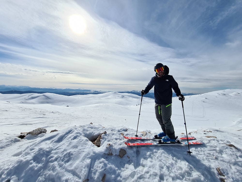 man in black jacket and black pants riding ski blades on snow covered ground during daytime