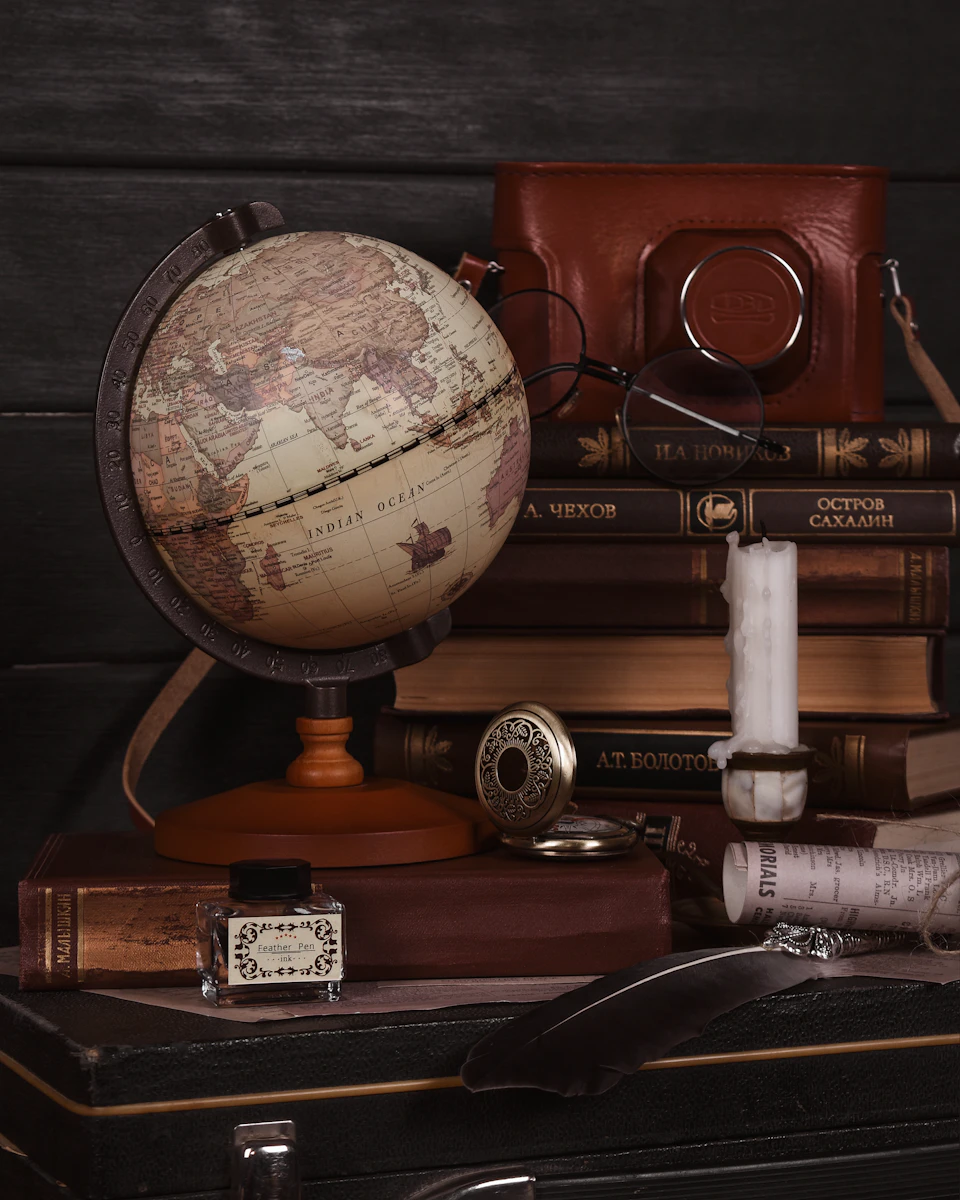 Antique globe with map of Europe and Asia on wooden surface surrounded by objects