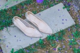 A pair of nude block heels resting on cobblestone city streets at sunset.