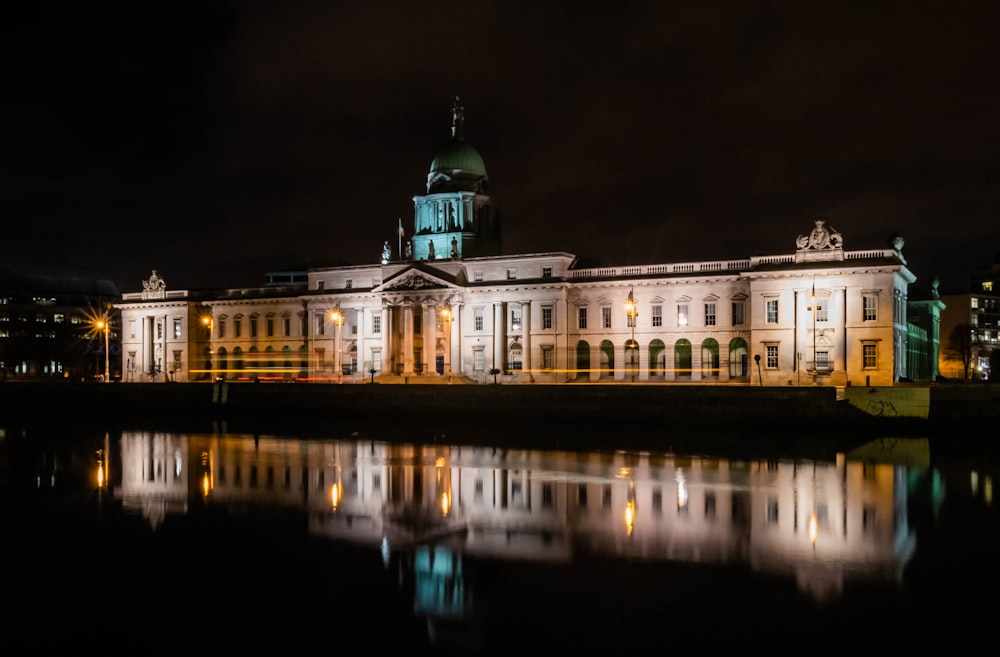 white and green concrete building near body of water during night time