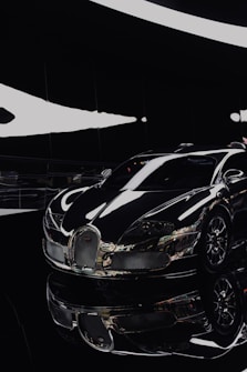 A sleek, luxury sports car with a glossy black finish is prominently displayed in a modern, well-lit showroom. The car's smooth curves and shiny chrome accents reflect light, adding to its futuristic and high-end appearance. The setting is minimalistic, enhancing the car's striking design.