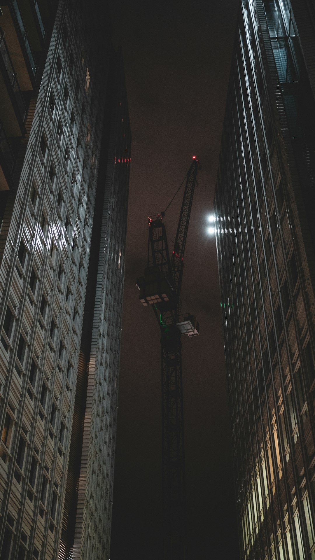 green crane in between high rise buildings during night time