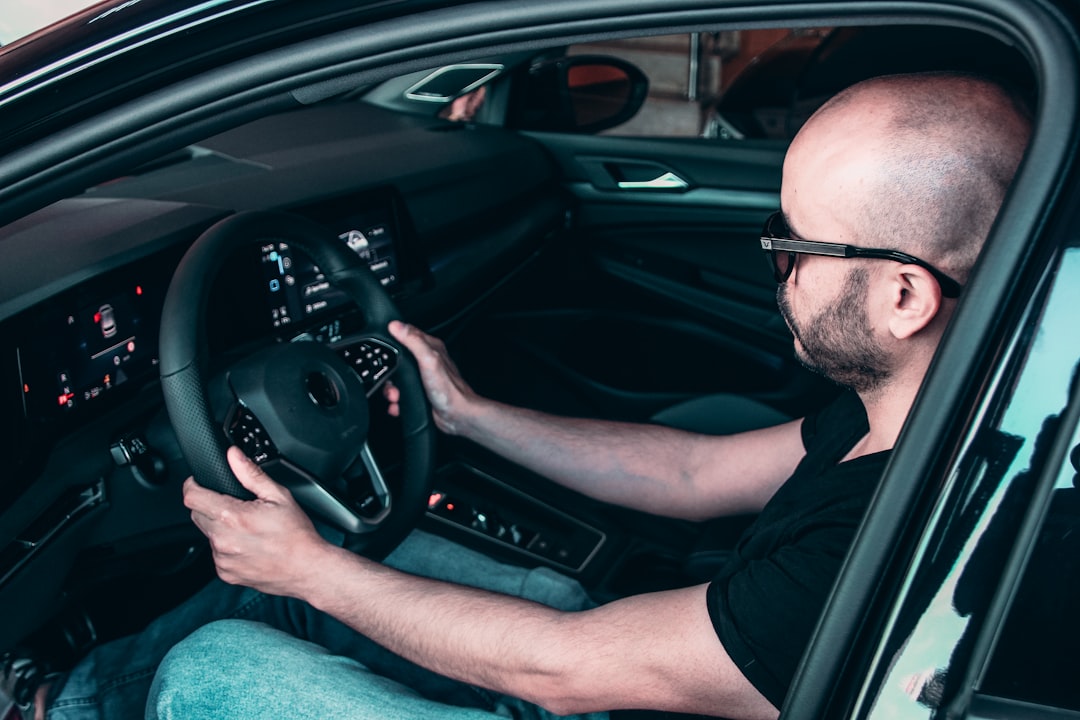 man in black framed eyeglasses driving car