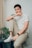 man in white crew neck t-shirt and brown pants sitting on white chair