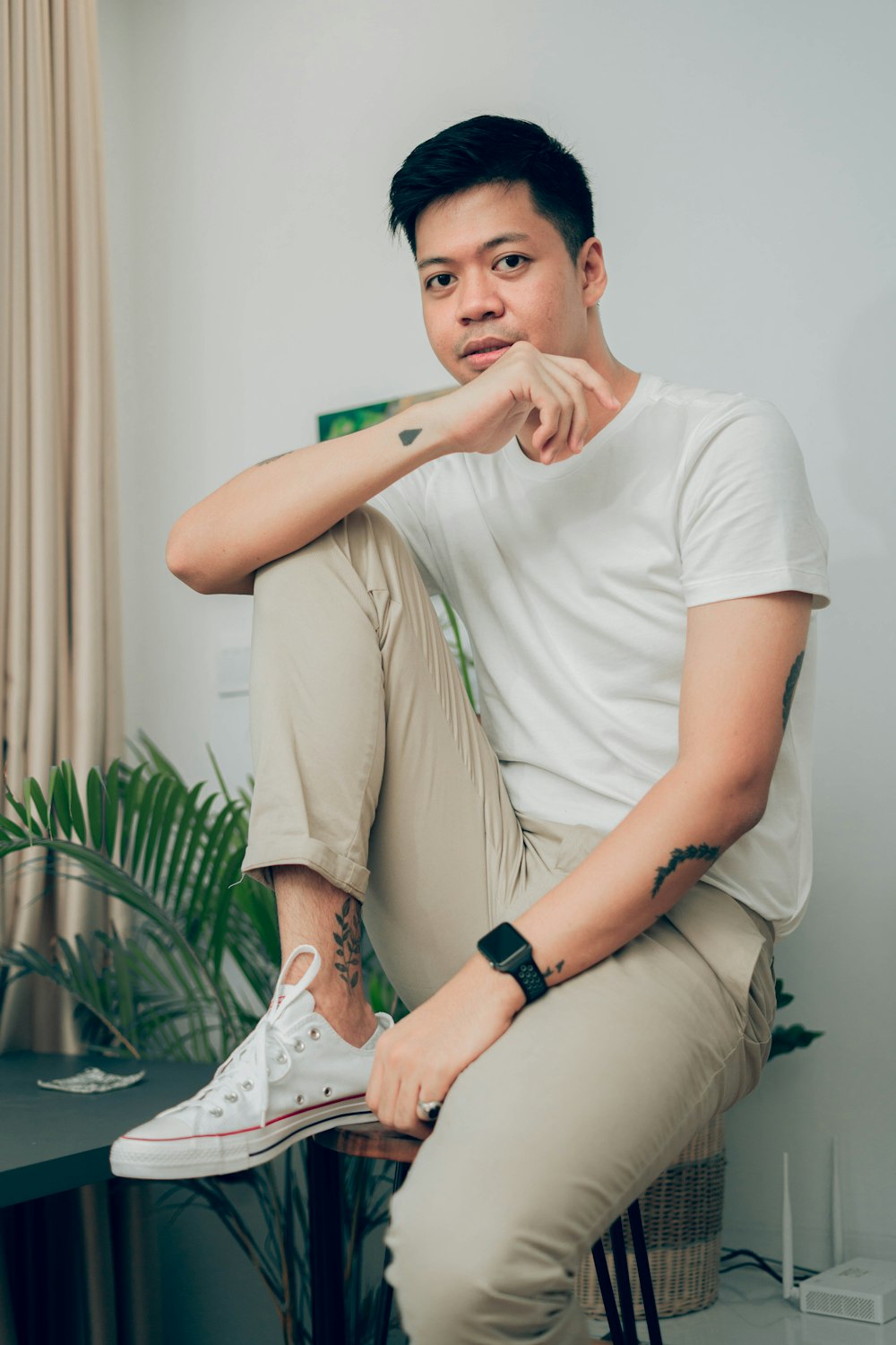 man in white crew neck t-shirt and brown pants sitting on white chair