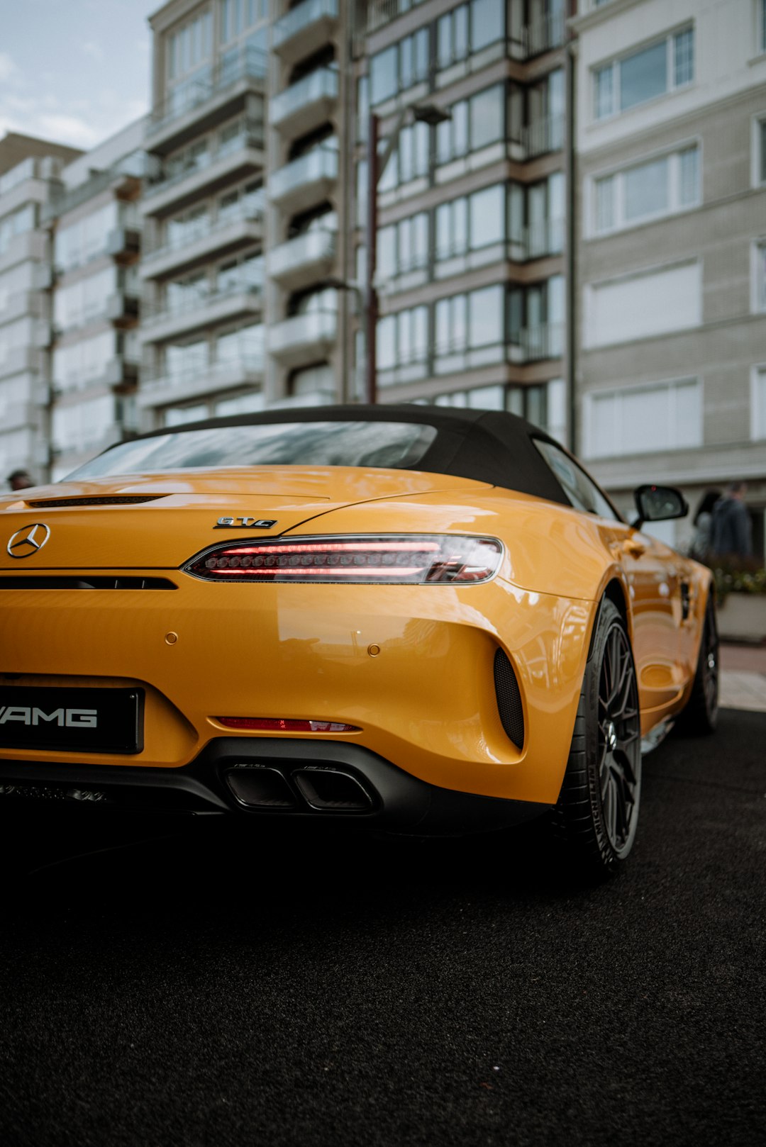 yellow porsche 911 parked near white building during daytime