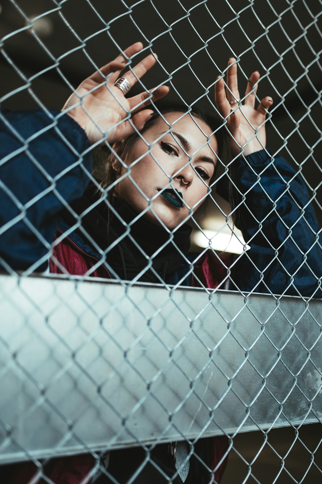 woman in blue shirt leaning on chain link fence