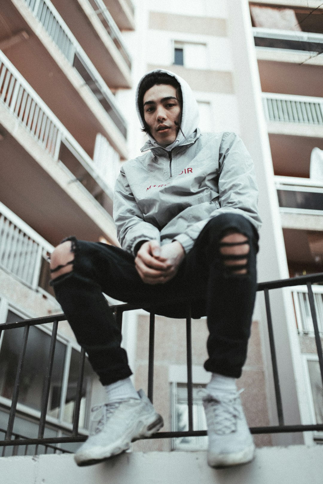 man in gray hoodie sitting on white staircase