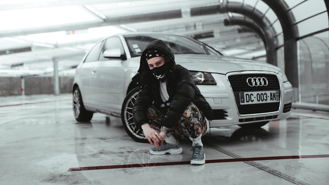 man in black jacket and black helmet standing beside white car